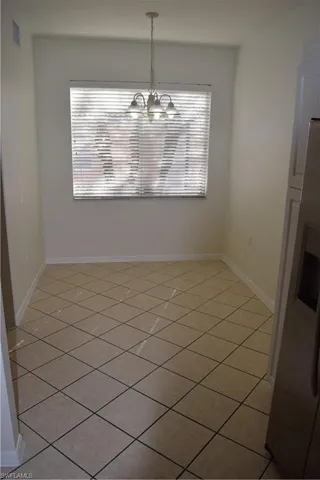 Unfurnished dining area with light tile patterned flooring and a chandelier