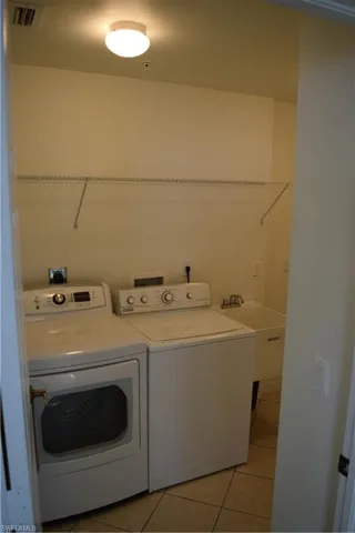 Laundry area with light tile patterned floors and washer and clothes dryer