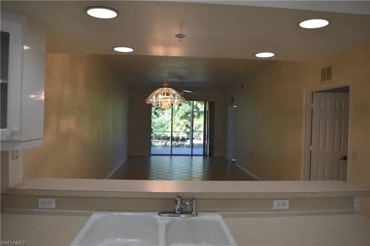 Kitchen featuring light countertops, hanging light fixtures, recessed lighting, white cabinets, and open floor plan
