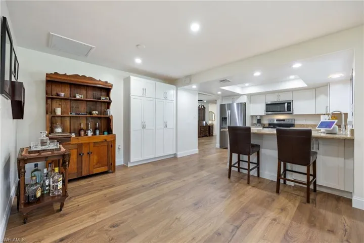 Kitchen with a tray ceiling, appliances with stainless steel finishes, white cabinets, light wood-style floors, and recessed lighting