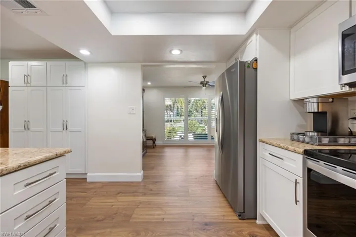 Kitchen featuring white cabinets, stainless steel appliances, light wood-style floors, and visible vents