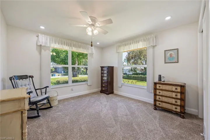 Sitting room with baseboards, ceiling fan, carpet, and a healthy amount of sunlight