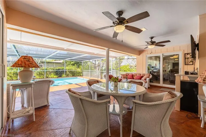 View of patio / terrace with an outdoor pool, outdoor dining space, glass enclosure, and ceiling fan