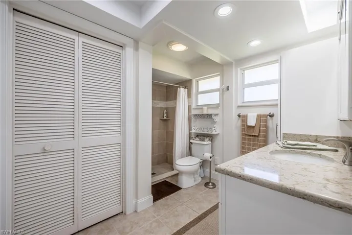 Full bath featuring a closet, a shower stall, toilet, tile patterned floors, and vanity