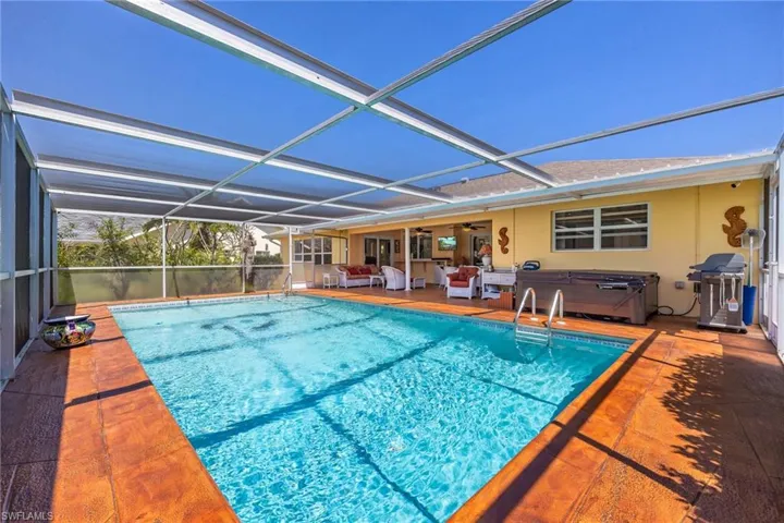 Outdoor pool with glass enclosure, ceiling fan, a grill, a jacuzzi, and a patio area