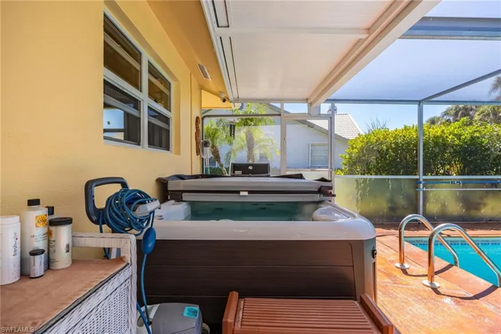 View of patio / terrace with an outdoor pool, glass enclosure, and a hot tub
