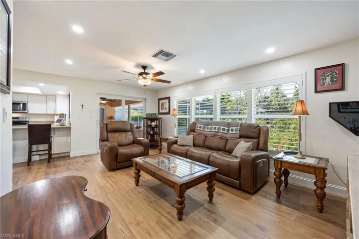 Living area featuring light wood-style flooring, plenty of natural light, ceiling fan, and visible vents