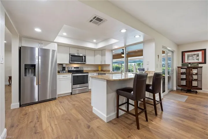 Kitchen with white cabinets, visible vents, a peninsula, light wood finished floors, and stainless steel appliances