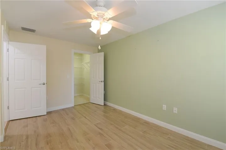 Unfurnished bedroom with a spacious closet, a closet, light wood-type flooring, and ceiling fan