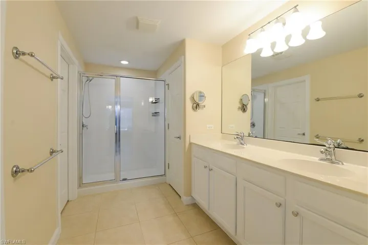 Bathroom featuring vanity, tile patterned flooring, and a shower with door