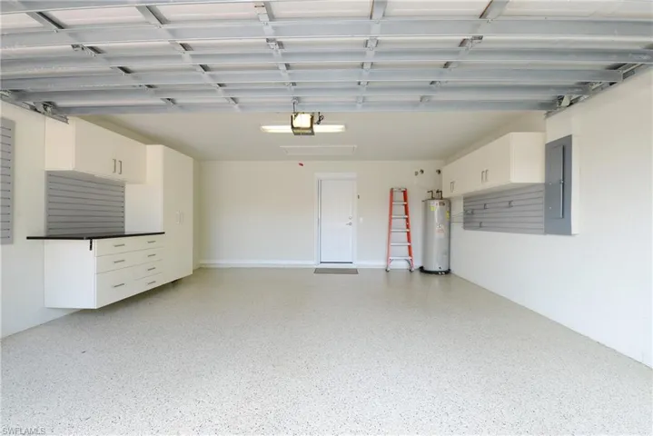 Garage featuring water heater, electric panel, and a garage door opener
