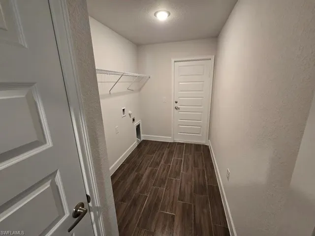 Laundry area with hookup for a washing machine, electric dryer hookup, a textured ceiling, and dark hardwood / wood-style floors