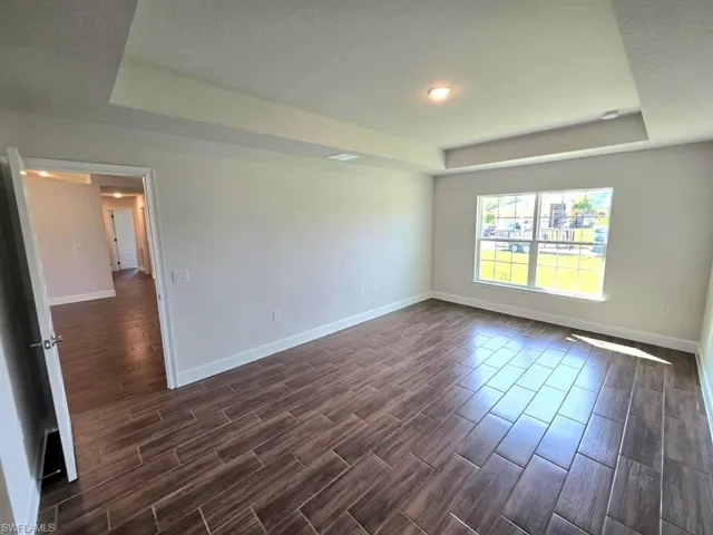 Empty room with dark wood-type flooring, a textured ceiling, and a tray ceiling
