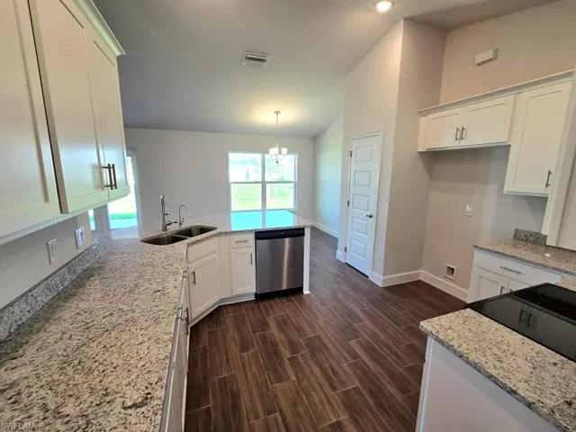 Kitchen featuring lofted ceiling, dark hardwood / wood-style floors, sink, stainless steel dishwasher, and white cabinetry