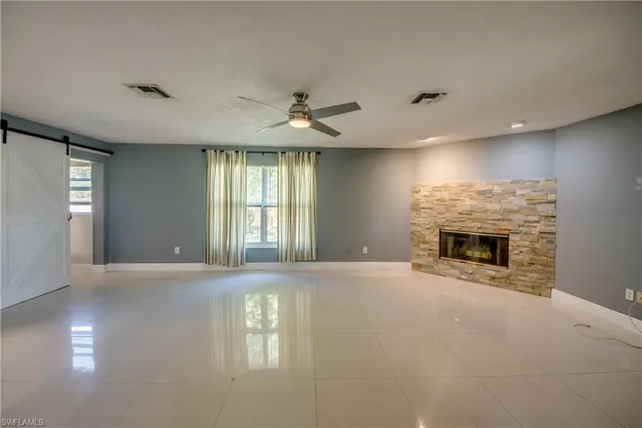 Unfurnished living room with a barn door, plenty of natural light, and light tile patterned floors