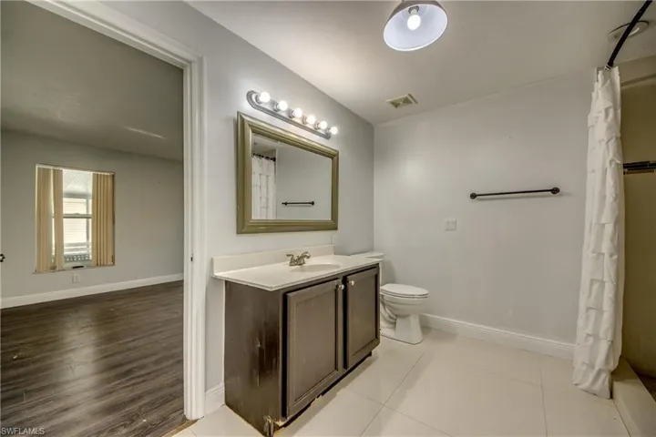 Full bath with curtained shower, vanity, and light tile patterned floors