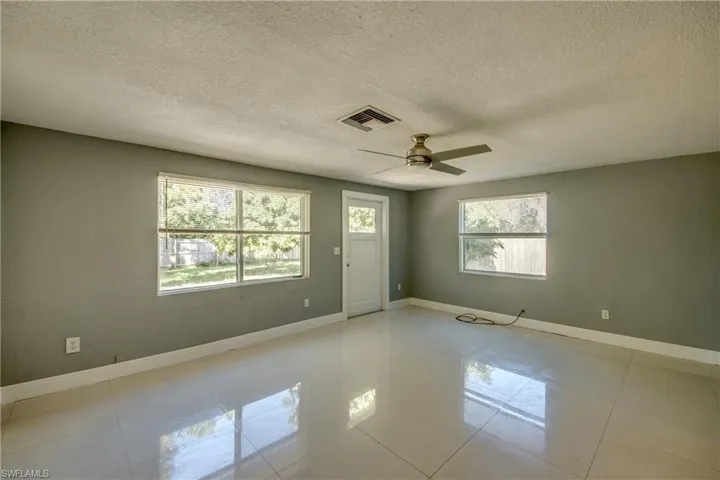 Spare room with a textured ceiling, light tile patterned floors, and ceiling fan