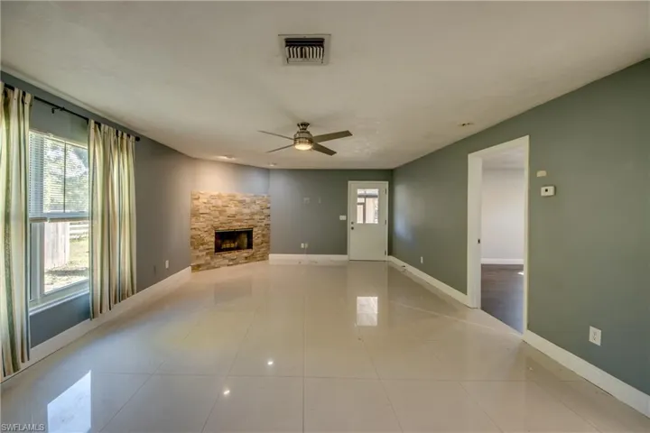Unfurnished living room featuring a fireplace, a ceiling fan, and light tile patterned floors