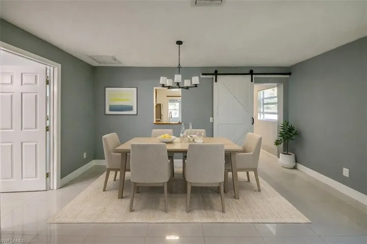 Staged virtually Dining space with a barn door, a chandelier, and light tile patterned floors