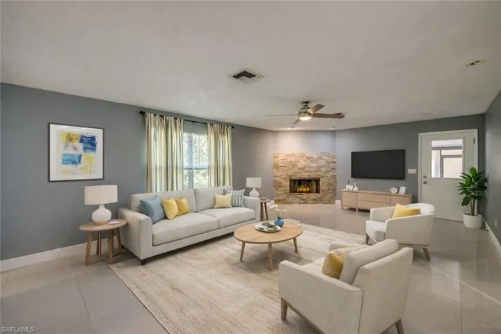 Virtually staged Living area featuring a stone fireplace, a ceiling fan, and tile patterned floors