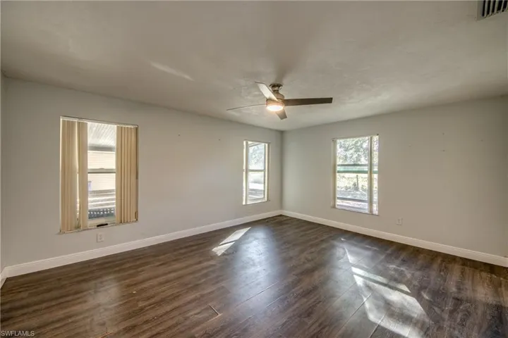 Primary bedroom featuring dark wood-style floors and ceiling fan