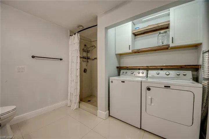 Laundry room featuring light tile patterned floors and washing machine and dryer