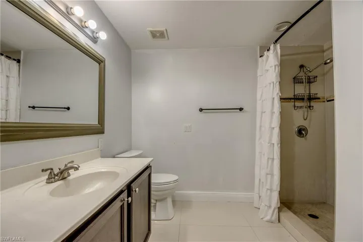 Bathroom with a stall shower, vanity, and light tile patterned flooring