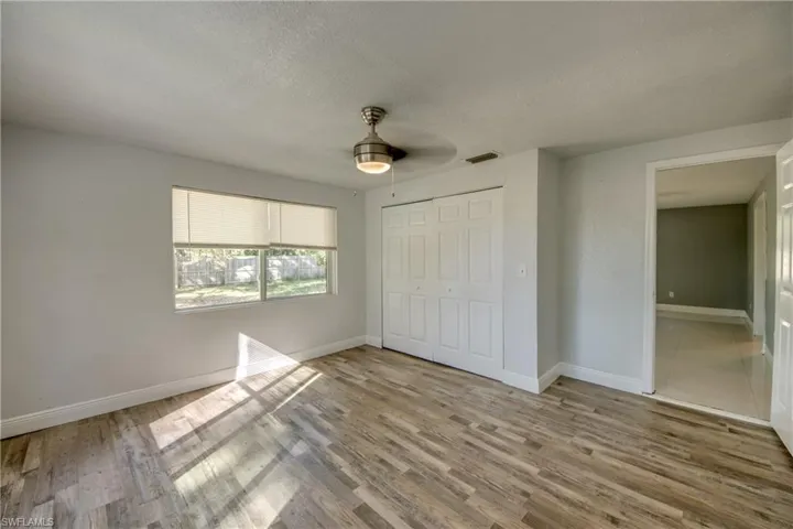 Unfurnished bedroom featuring a textured ceiling, a closet, a ceiling fan, and light wood finished floors