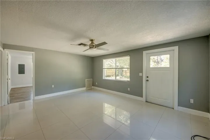 Foyer featuring a textured ceiling, a ceiling fan, light tile patterned flooring, and electric panel