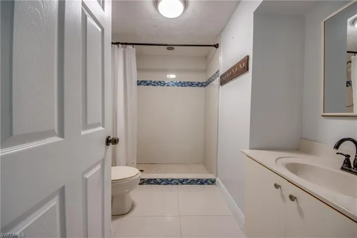 Full bathroom featuring tiled shower, vanity, and light tile patterned floors