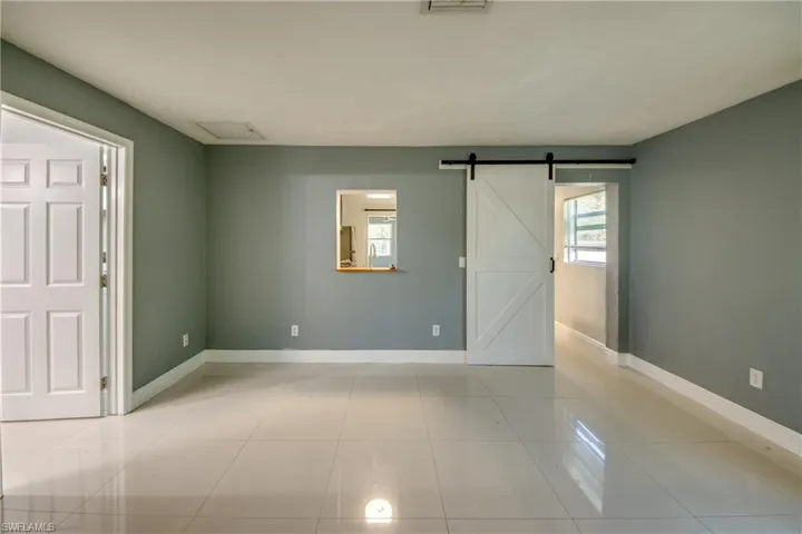 Empty room featuring a barn door and light tile patterned floors
