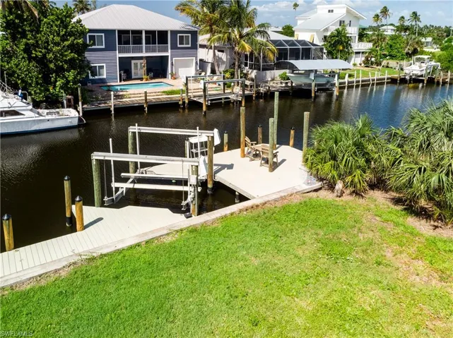 Dock with boat lift, a water view, and a lawn