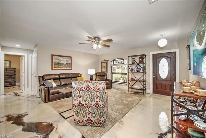 Living area featuring a ceiling fan and marble finish floor