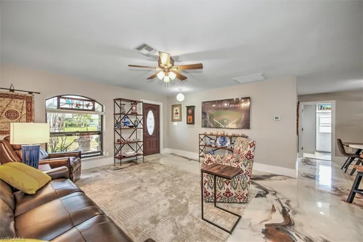 Living room featuring a ceiling fan, a healthy amount of sunlight, visible vents, and marble finish floor