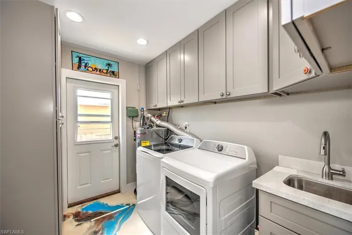Laundry area featuring washer and dryer, a sink, water heater, recessed lighting, and cabinet space