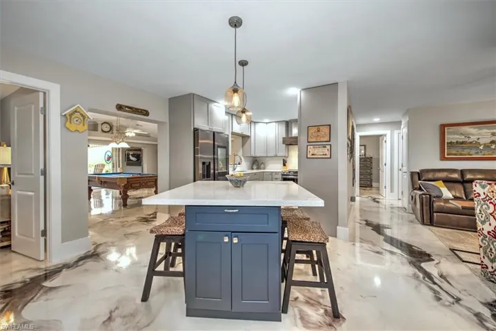 Kitchen featuring marble finish floor, a breakfast bar area, billiards, and stainless steel fridge