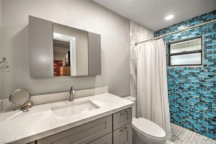 Full bath with toilet, a stall shower, and vanity