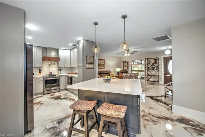 Kitchen featuring open floor plan, electric stove, visible vents, and marble finish floor