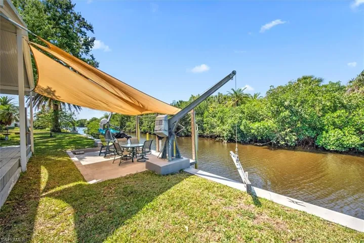 View of dock with a water view, a lawn, and a patio