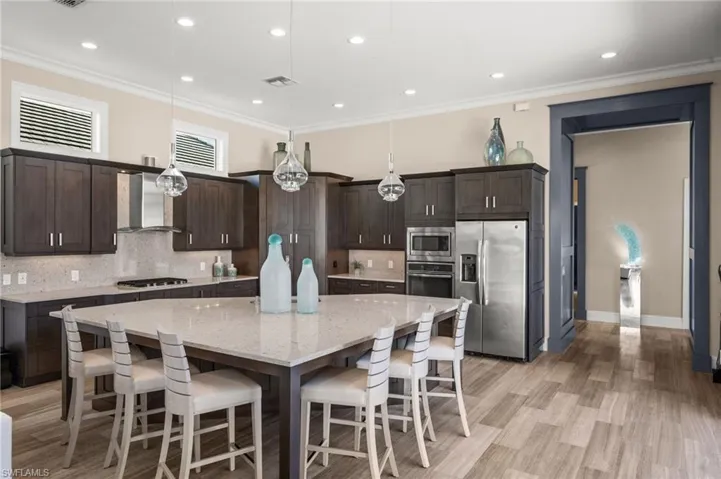 Kitchen featuring a kitchen breakfast bar, decorative light fixtures, appliances with stainless steel finishes, tasteful backsplash, and recessed lighting