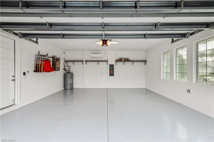 Garage with electric water heater, electric panel, and a garage door opener