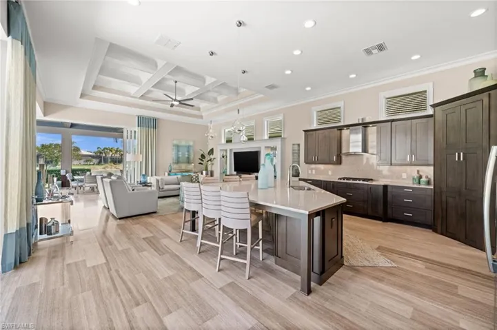 Kitchen with crown molding, ceiling fan, coffered ceiling, dark brown cabinetry, and recessed lighting