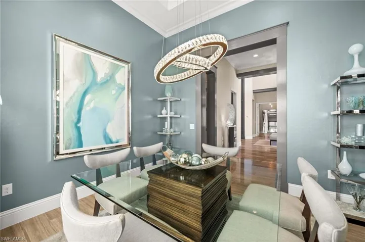 Dining area featuring wood finished floors, crown molding, and a chandelier