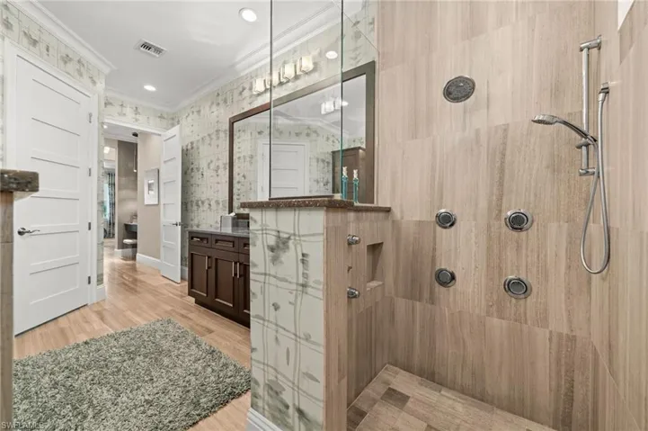 Bathroom with vanity, a tile shower, light wood-type flooring, crown molding, and wallpapered walls