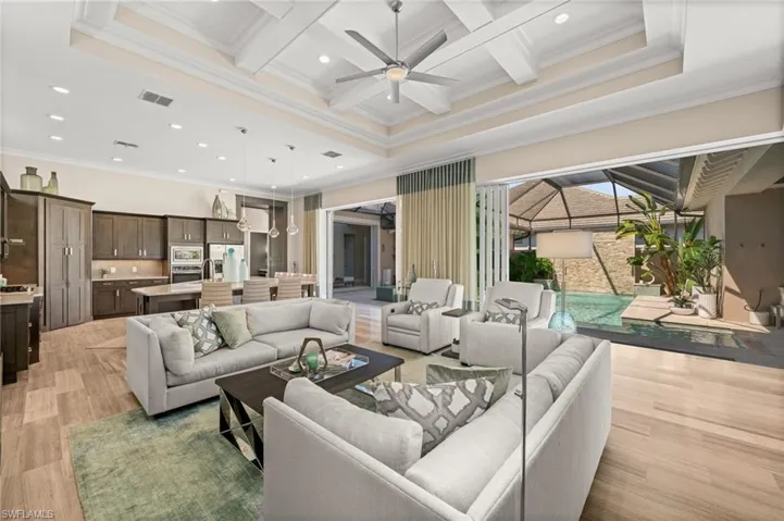 Living area featuring coffered ceiling, beam ceiling, recessed lighting, ornamental molding, and a ceiling fan