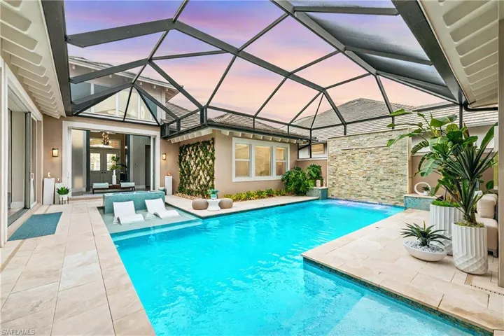 Swimming pool featuring a sunroom, a patio, and glass enclosure