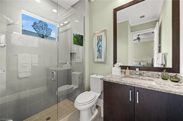 Full bath with a stall shower, vanity, crown molding, and ensuite bath