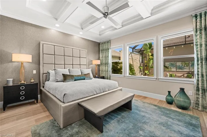 Bedroom featuring beam ceiling, light wood finished floors, ornamental molding, coffered ceiling, and ceiling fan