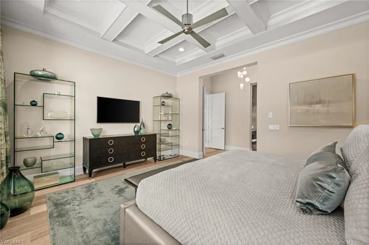 Bedroom featuring crown molding, coffered ceiling, wood finished floors, beam ceiling, and a ceiling fan