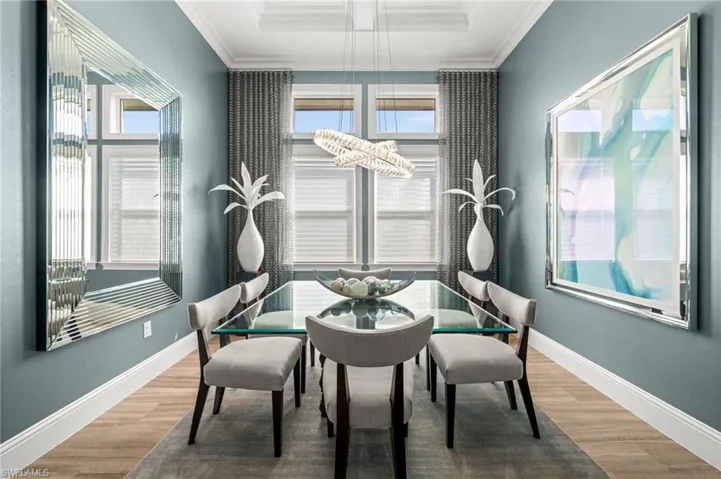 Dining space with ornamental molding, wood finished floors, and a raised ceiling